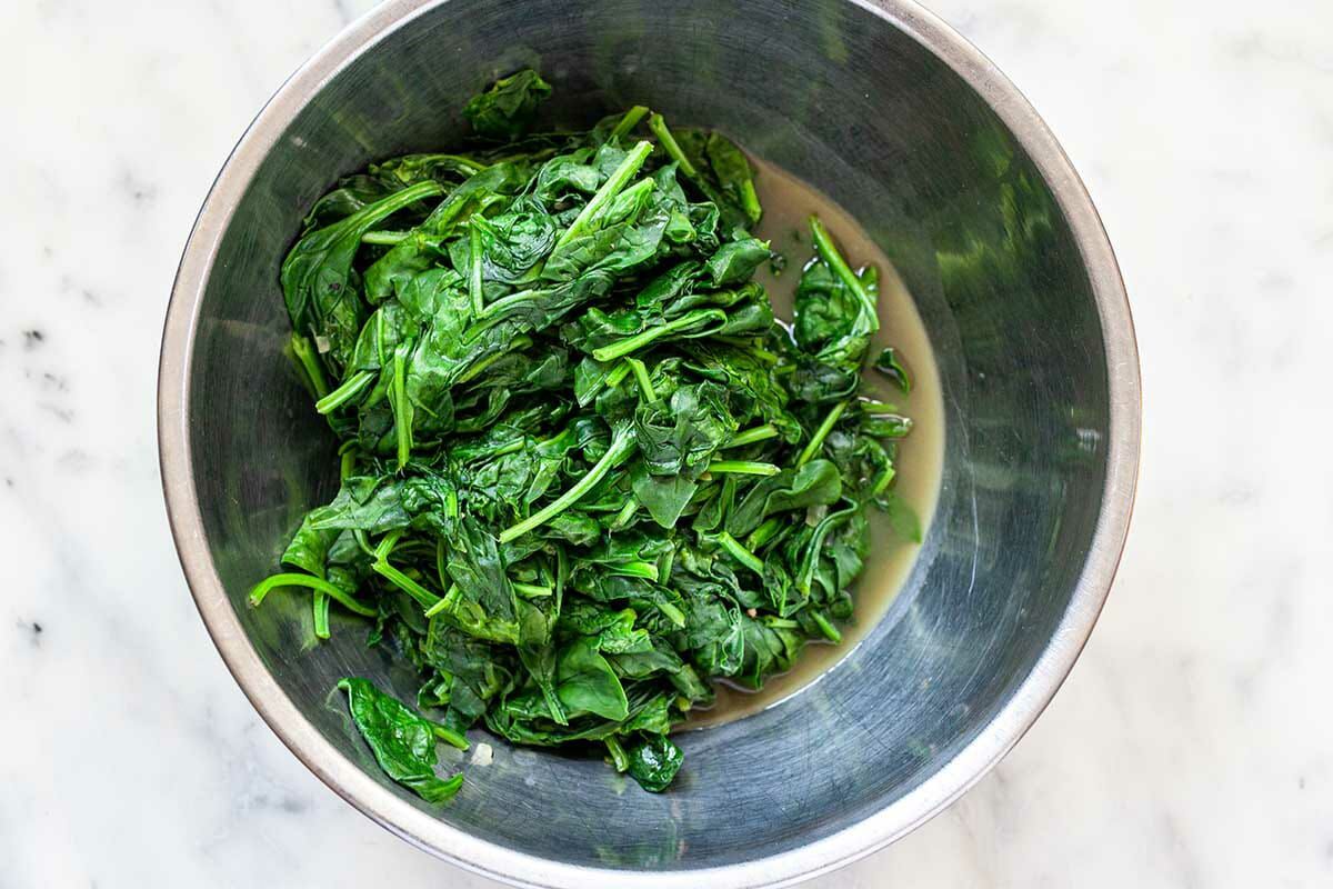 Sauteed spinach in a metal bowl for Easy Creamed Spinach.