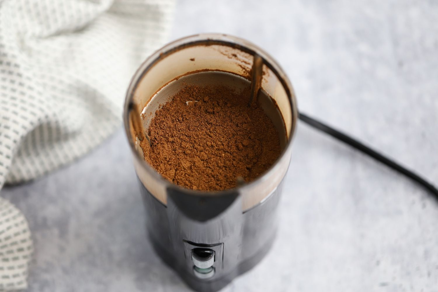 Ground Toasted Spices in a Spice Grinder Next to a Kitchen Towel