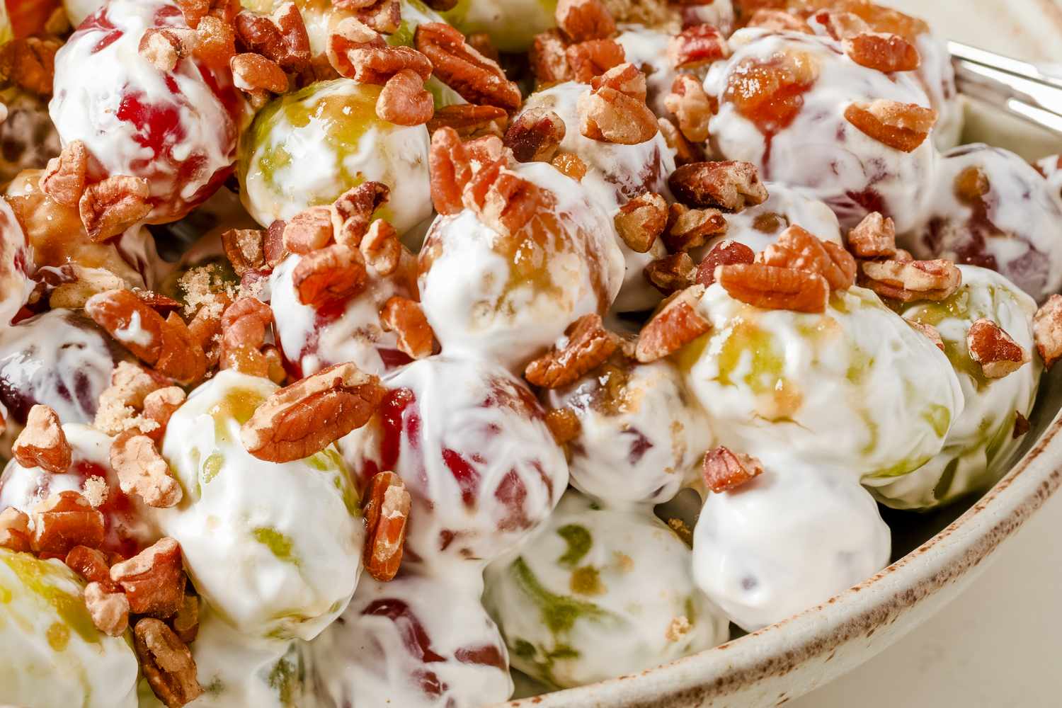 Bowl of grape salad with pecans and creamy topping