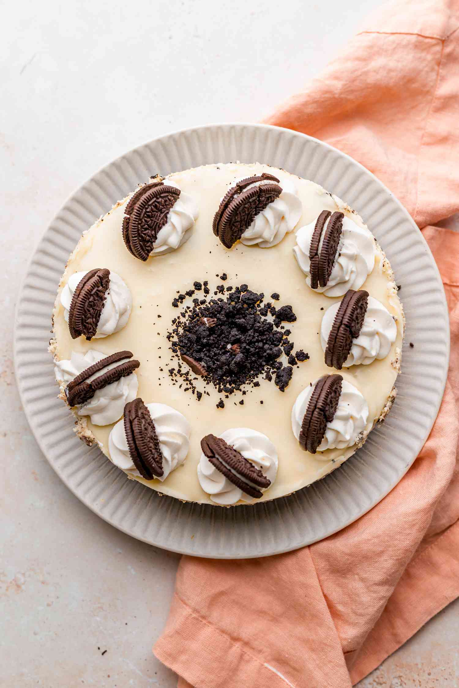 Oreo cheesecake on plate decorated with whipped cream and Oreos