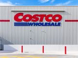Exterior of a Costco Wholesale store with the logo on the building front four red poles marking the sidewalk