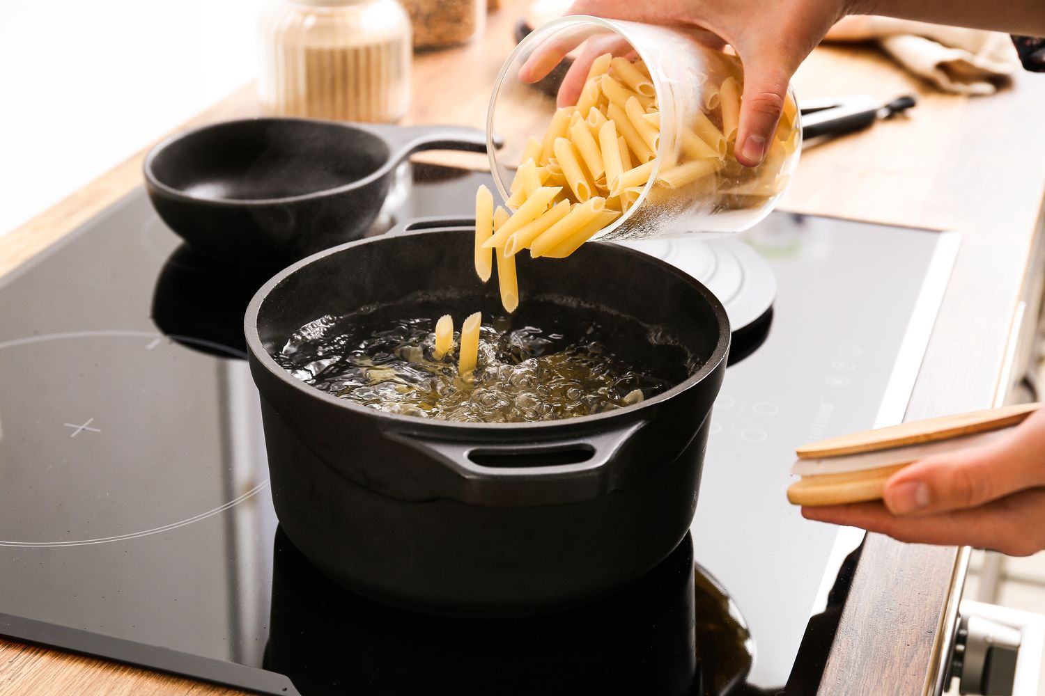 Pasta being added into a pot of boiling water on a stove