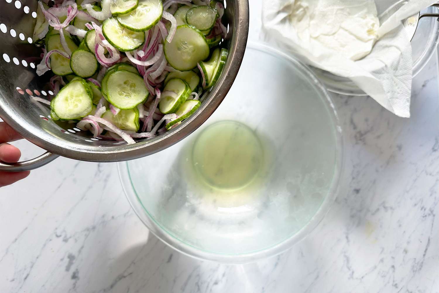 Preparation of a cucumber and onion salad over a marble countertop