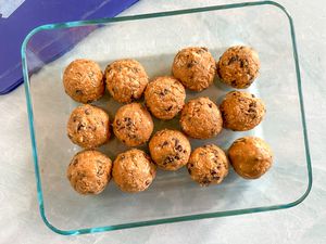 Overhead view of a clear glass bowl of fourteen energy balls on a marble counter