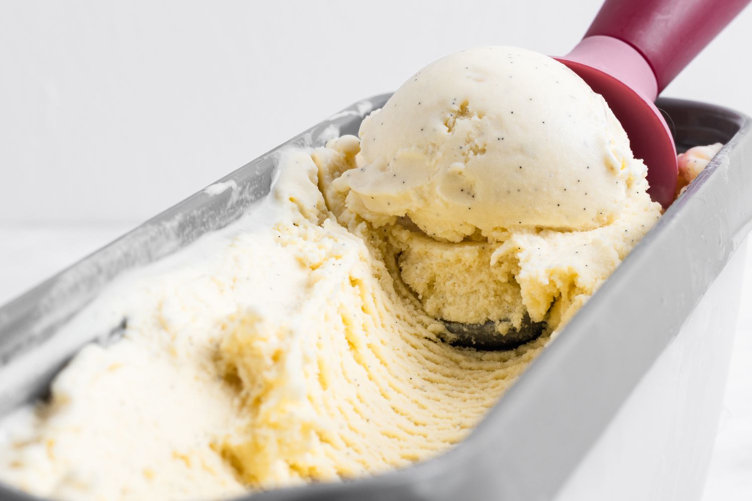 Scooping vanilla ice cream out of a container.