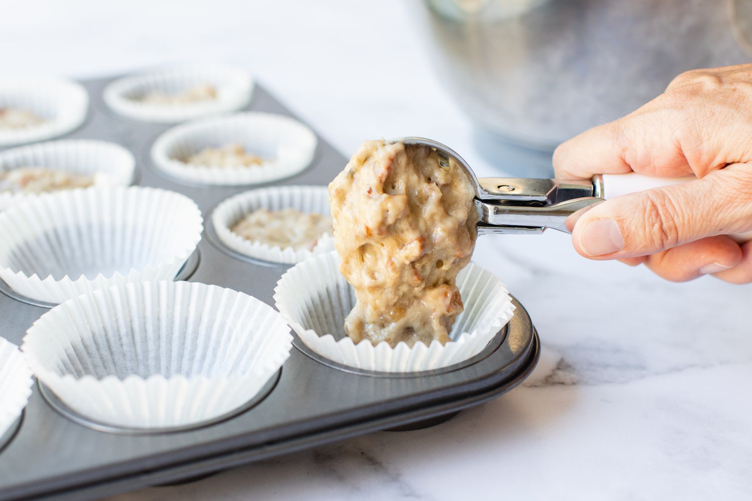 Scooping batter into muffin tins for Banana Nut Muffisn