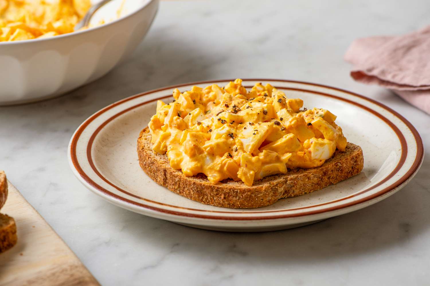 Side view of a toast topped with kimchi egg salad on a plate