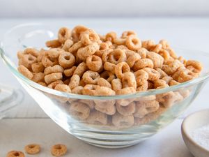 A bowl of fried Cheerios with butter and salt visible in the background