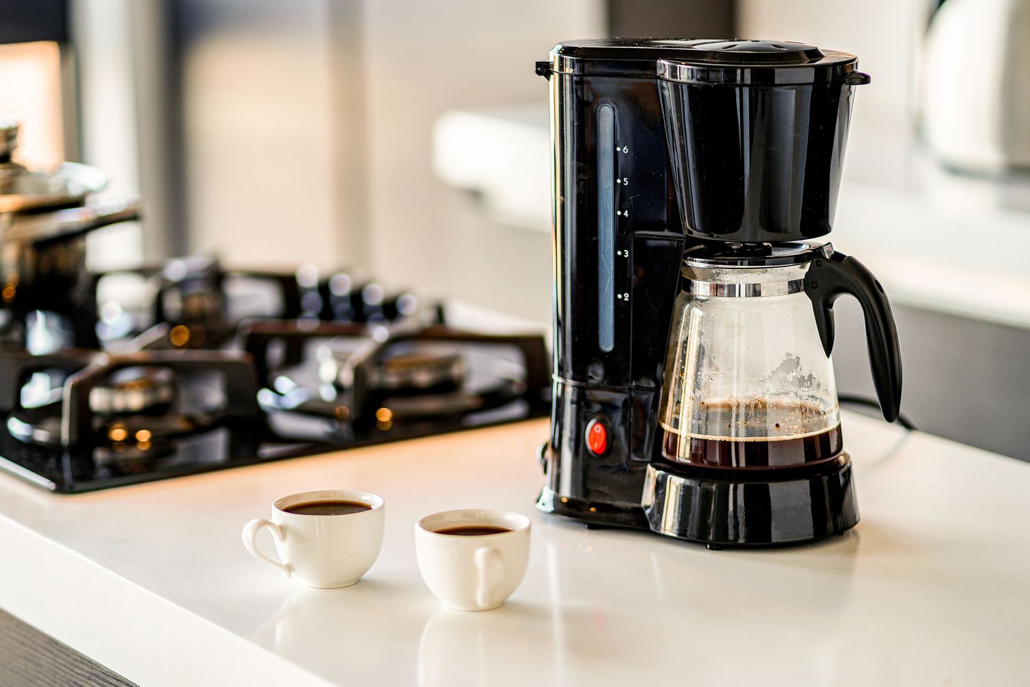 coffee maker on a countertop with 2 small cups of coffee