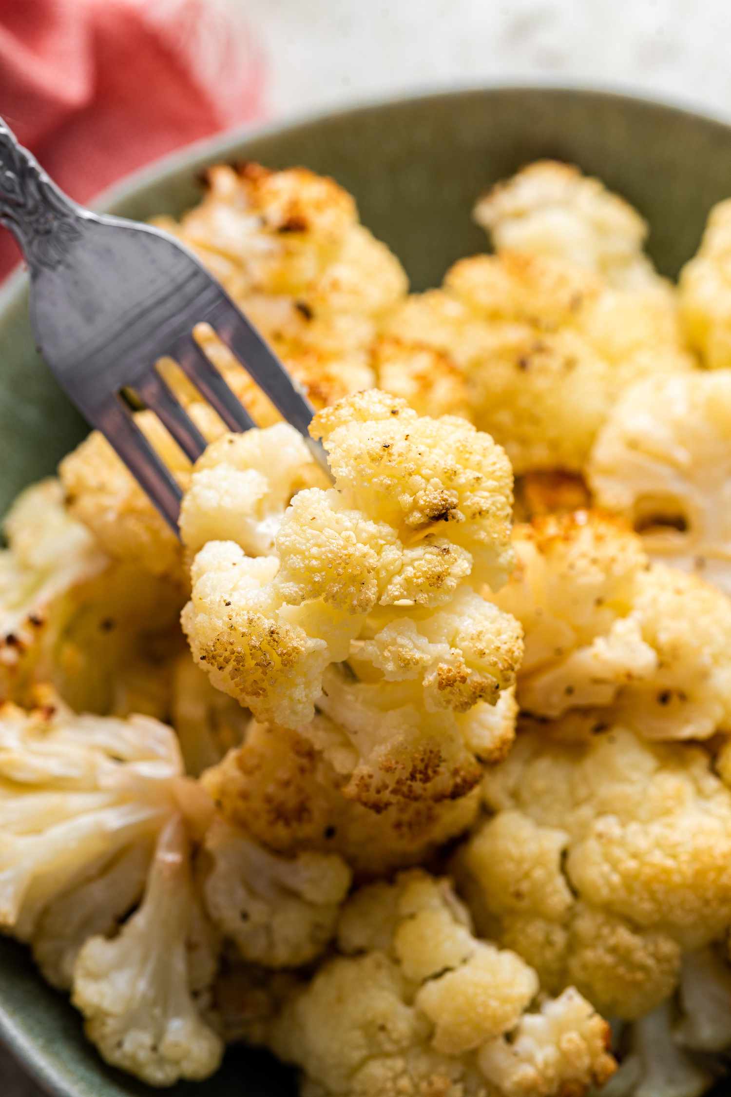 Roasted Cauliflower on a Fork and More in the Bowl underneath It