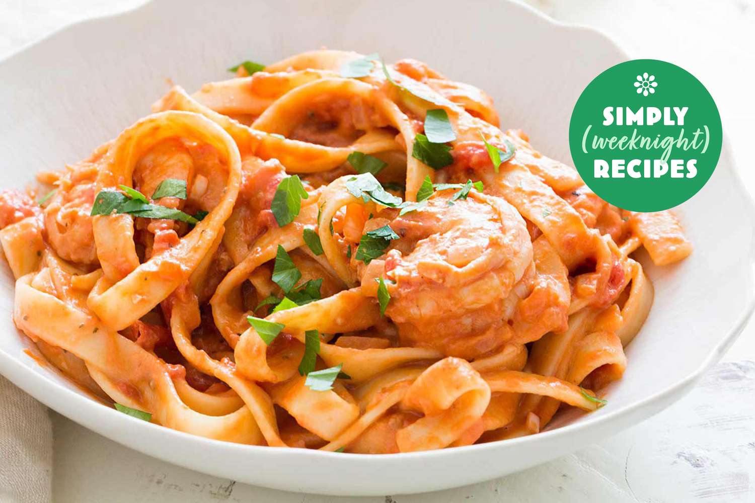 A bowl of pasta with shrimp in a creamy sauce labeled as a Simply Weeknight Recipe