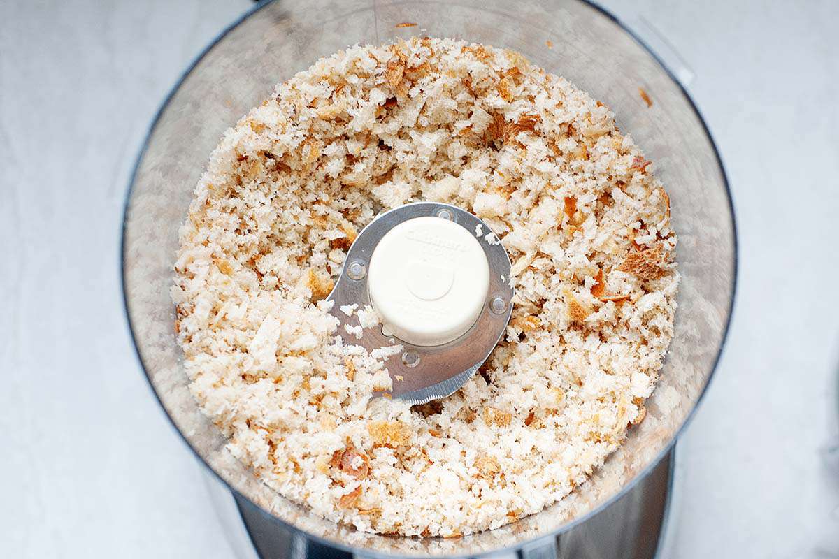 Overhead view of a food processor bowl with bread crumbs inside.