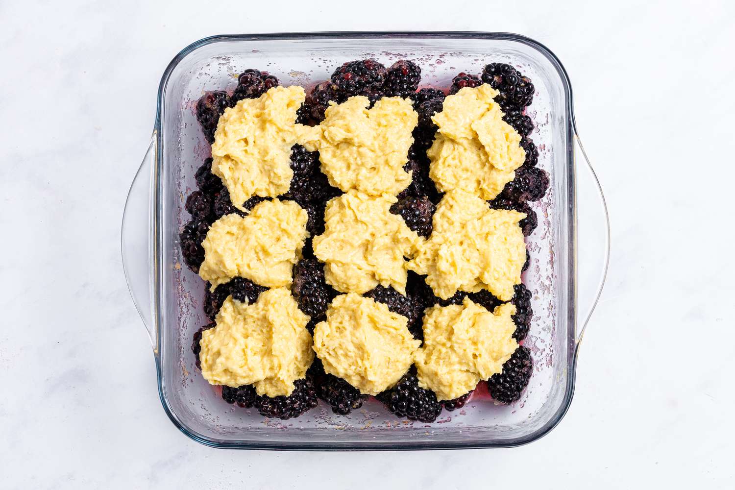 A baking dish with blackberry cobbler ready to be baked.