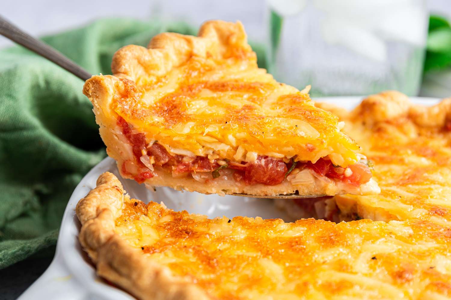 slice of tomato pie lifted from a pie pan with more (close-up)