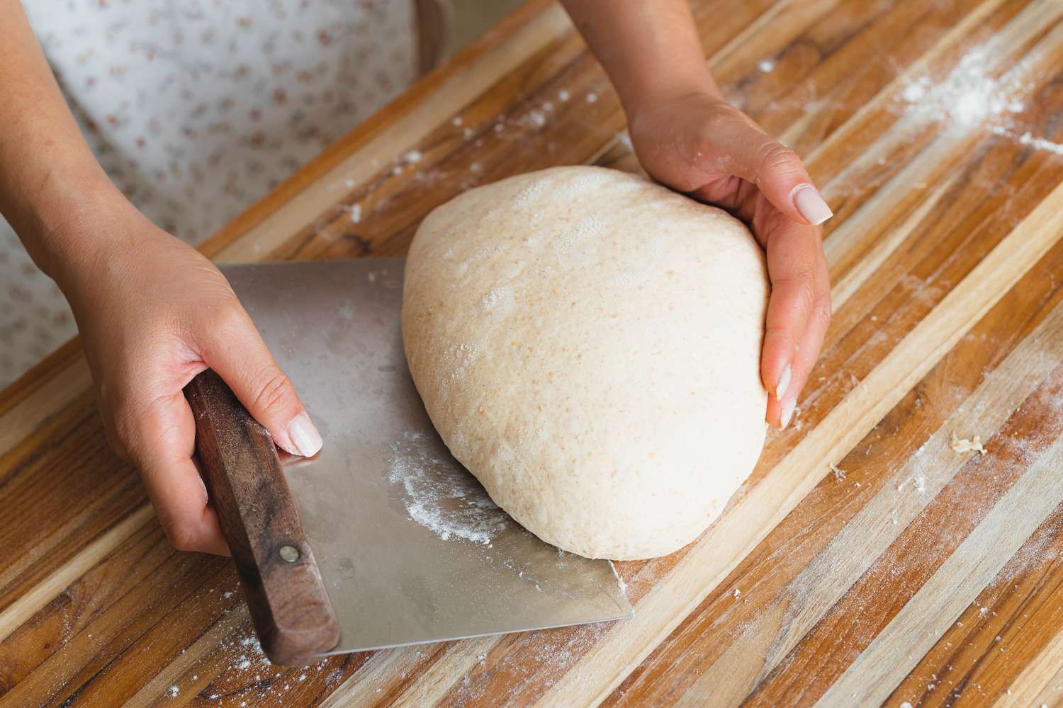 Using a bench scraper to lift dough off a counter.
