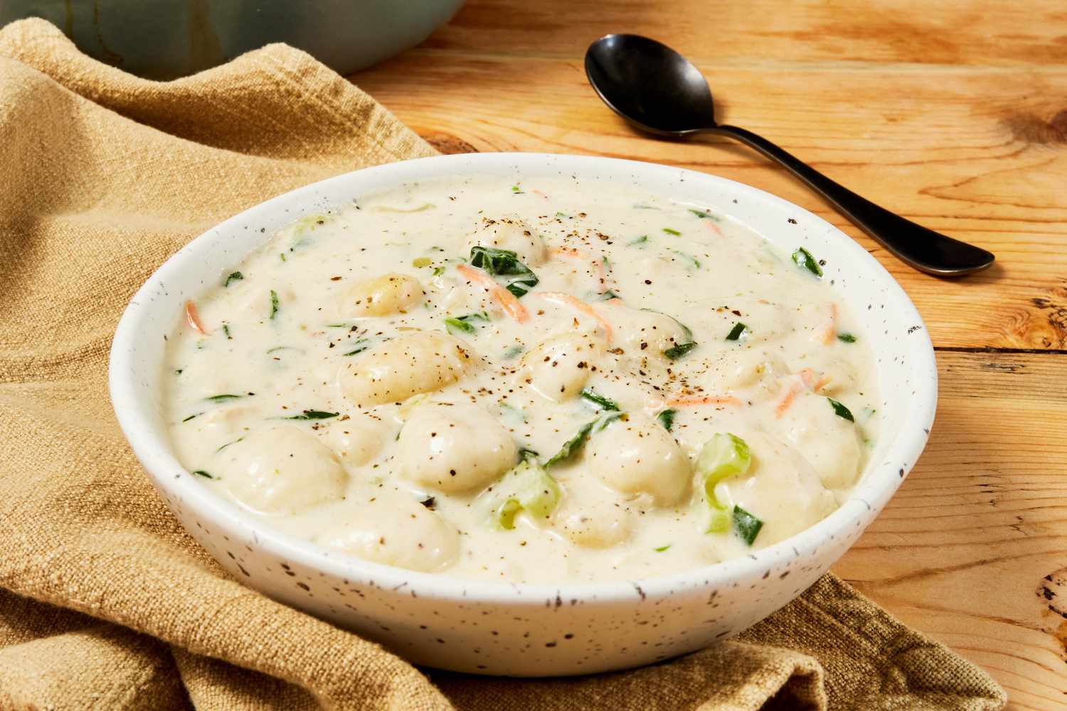 Bowl of copycat Olive Garden chicken and gnocchi soup on a beige table napkin 