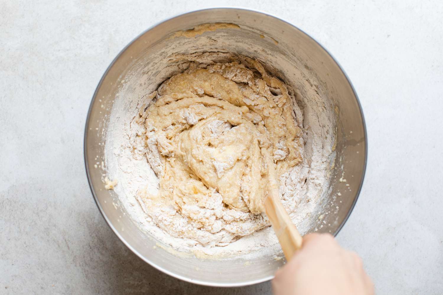 Dry Ingredients Mixed in with Wet Ingredients Using a Wooden Spoon