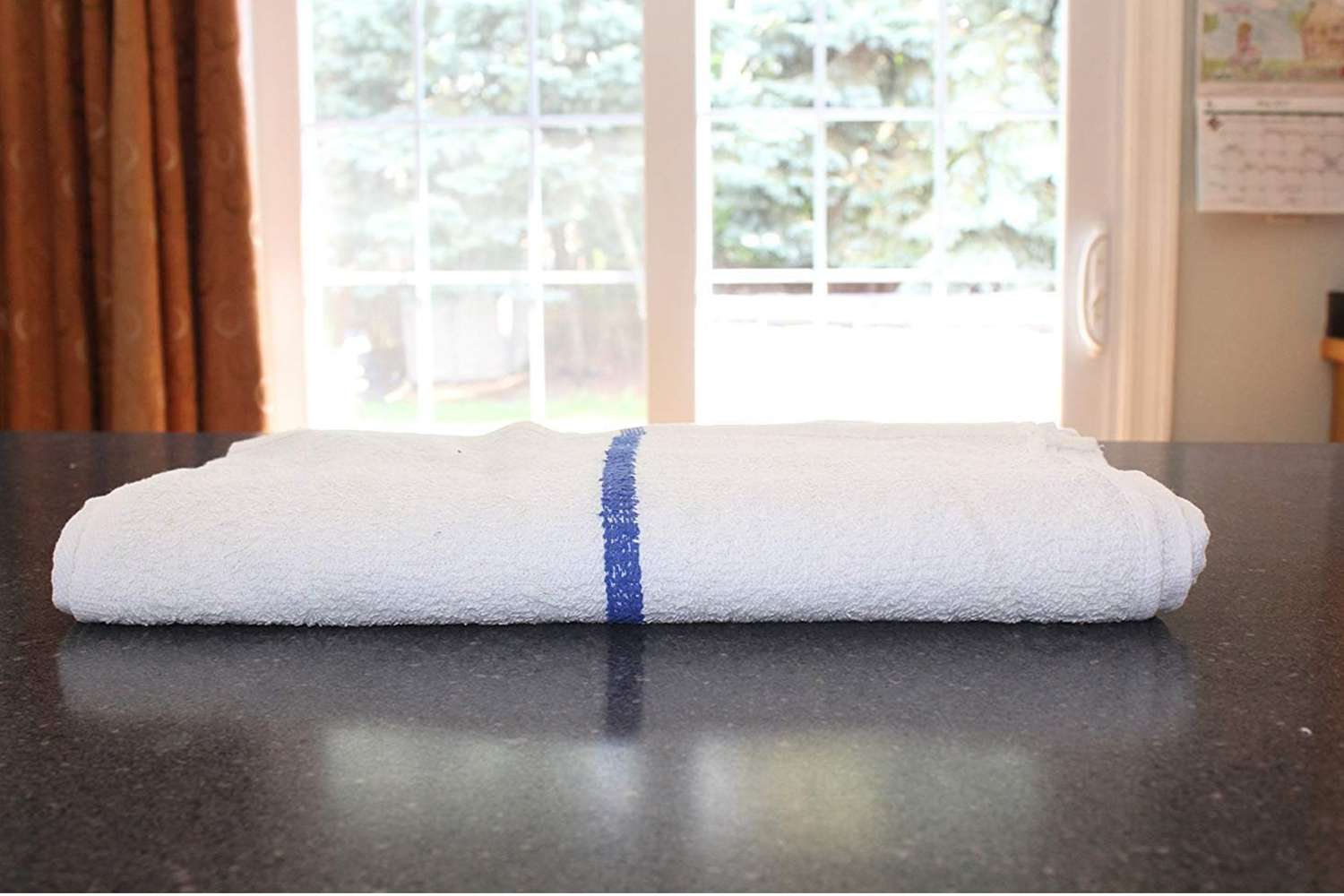 white towel with a blue stripe down the middle, folded and on a countertop
