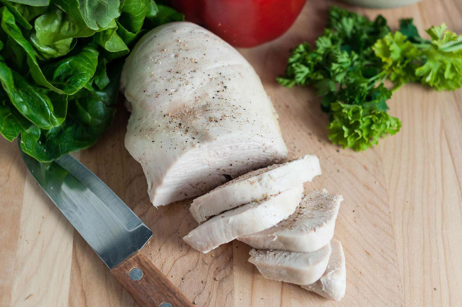 Overhead of a cooked chicken breast that is beginning to be sliced 
