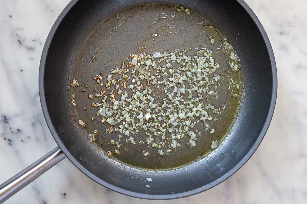 Finely shopped onions sauteed in butter to show how to make creamed spinach.