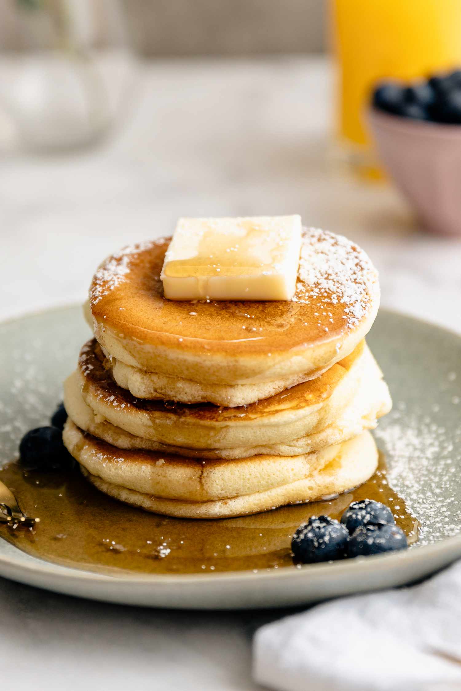 Plate of Japanese Souffle Pancakes Topped with Butter, Maple Syrup, Powdered Sugar, and Blueberries 