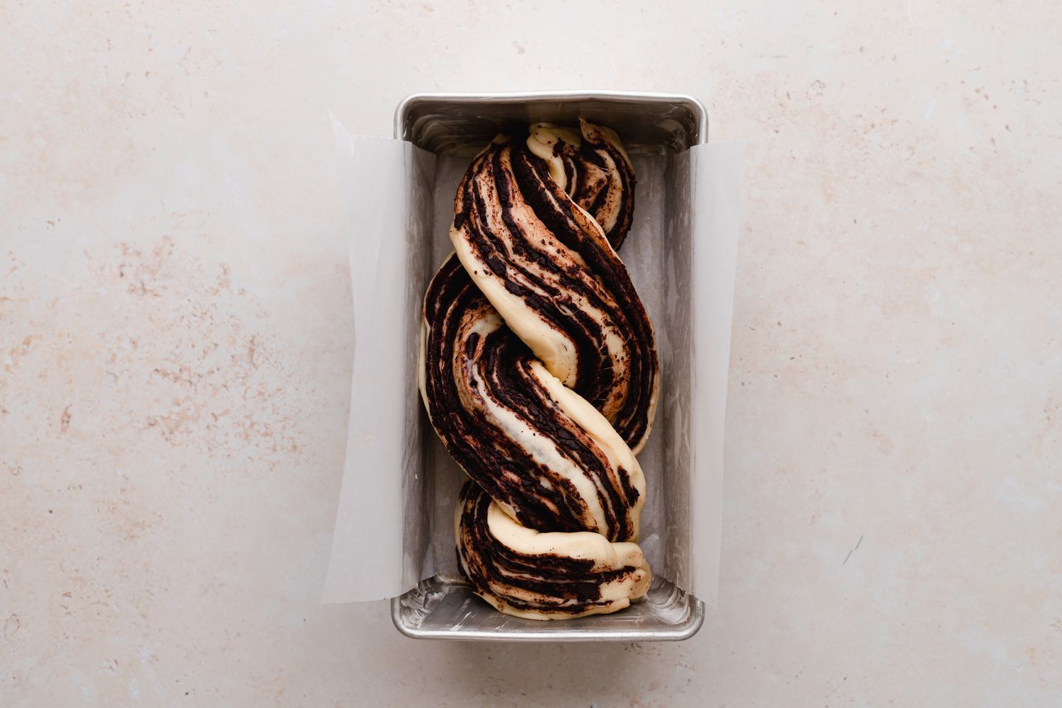 Braided chocolate babka in a loaf pan and ready to be baked.