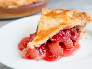 Slice of Strawberry Rhubarb Pie on a Plate, and in the Background, More in a Glass Pie Pan