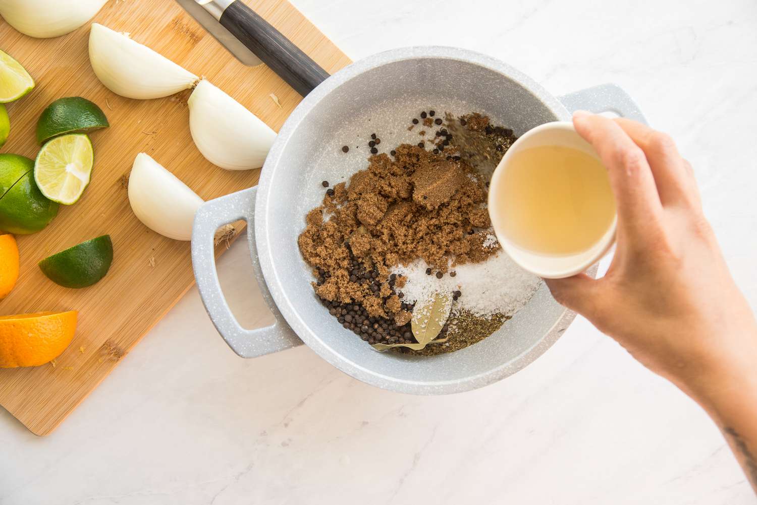 Brown Sugar, Vinegar, and Spices Added to Pot for Pork Chop Brine and Onions, Limes, and Oranges on Cutting Board