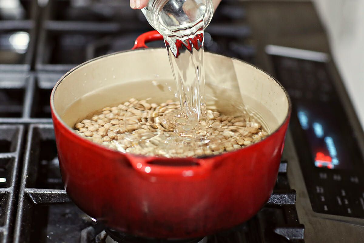 Water being poured into a Dutch oven of dried beans on the stovetop