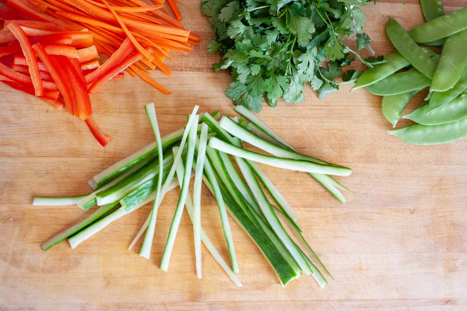 Vegetables on a cutting board for a vegetable rice noodle salad.