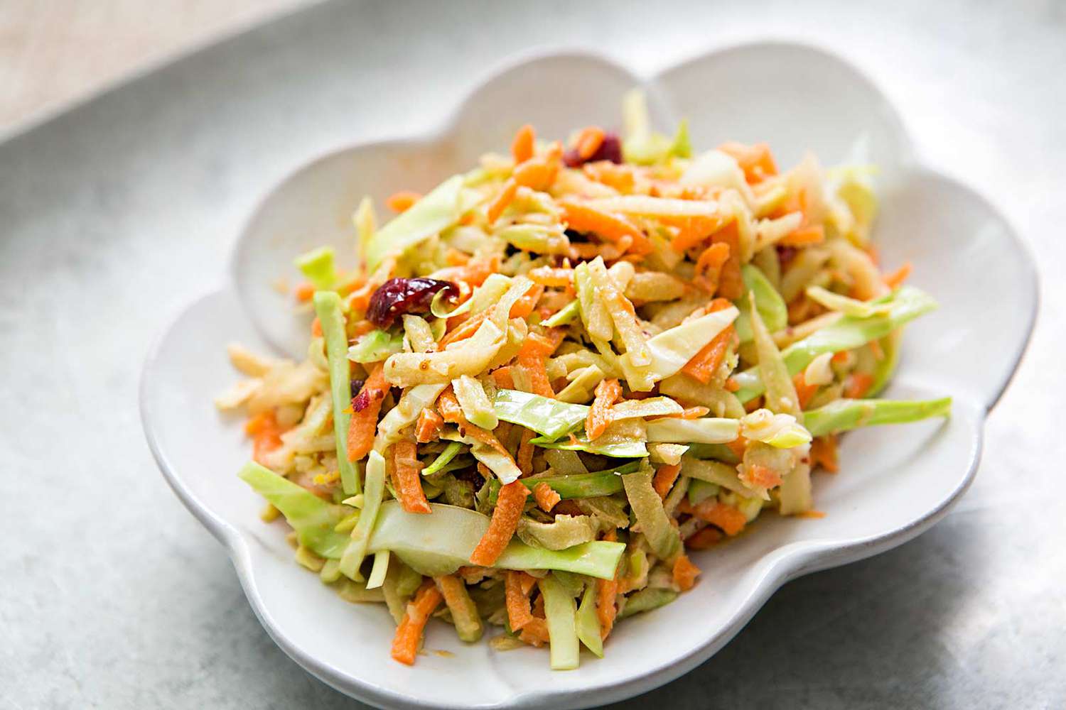 A dish of broccoli slaw with dried cranberries and nuts