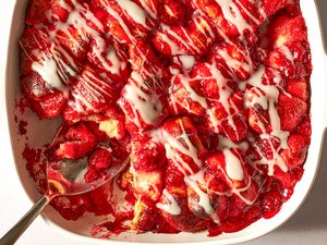 Closeup overhead shot of cherry cobbler in a baking dish, drizzled with a glaze