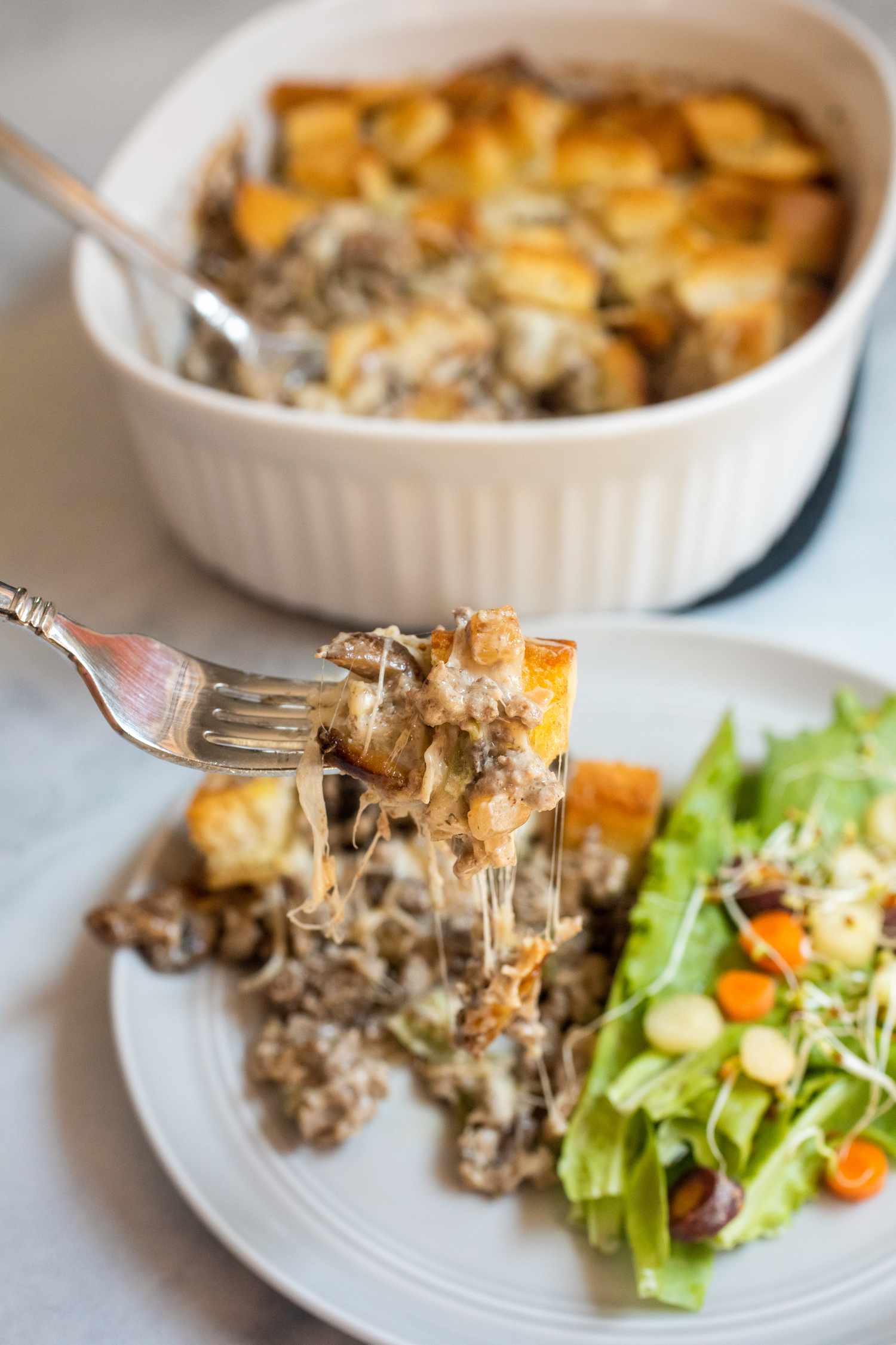 Fork lifting Philly cheesesteak from plate.