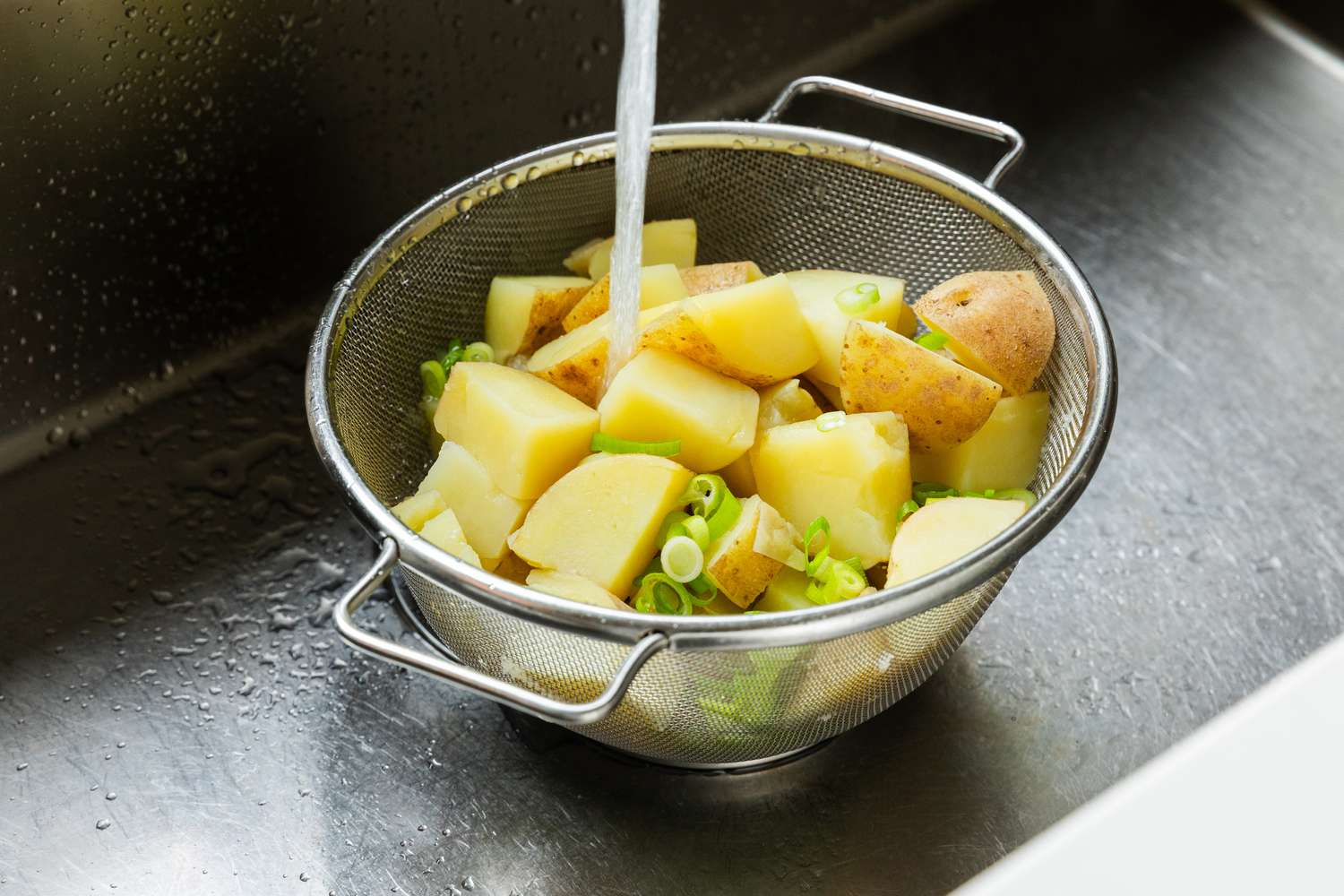 Potatoes and Sliced Onions Rinsed in a Colander in the Sink