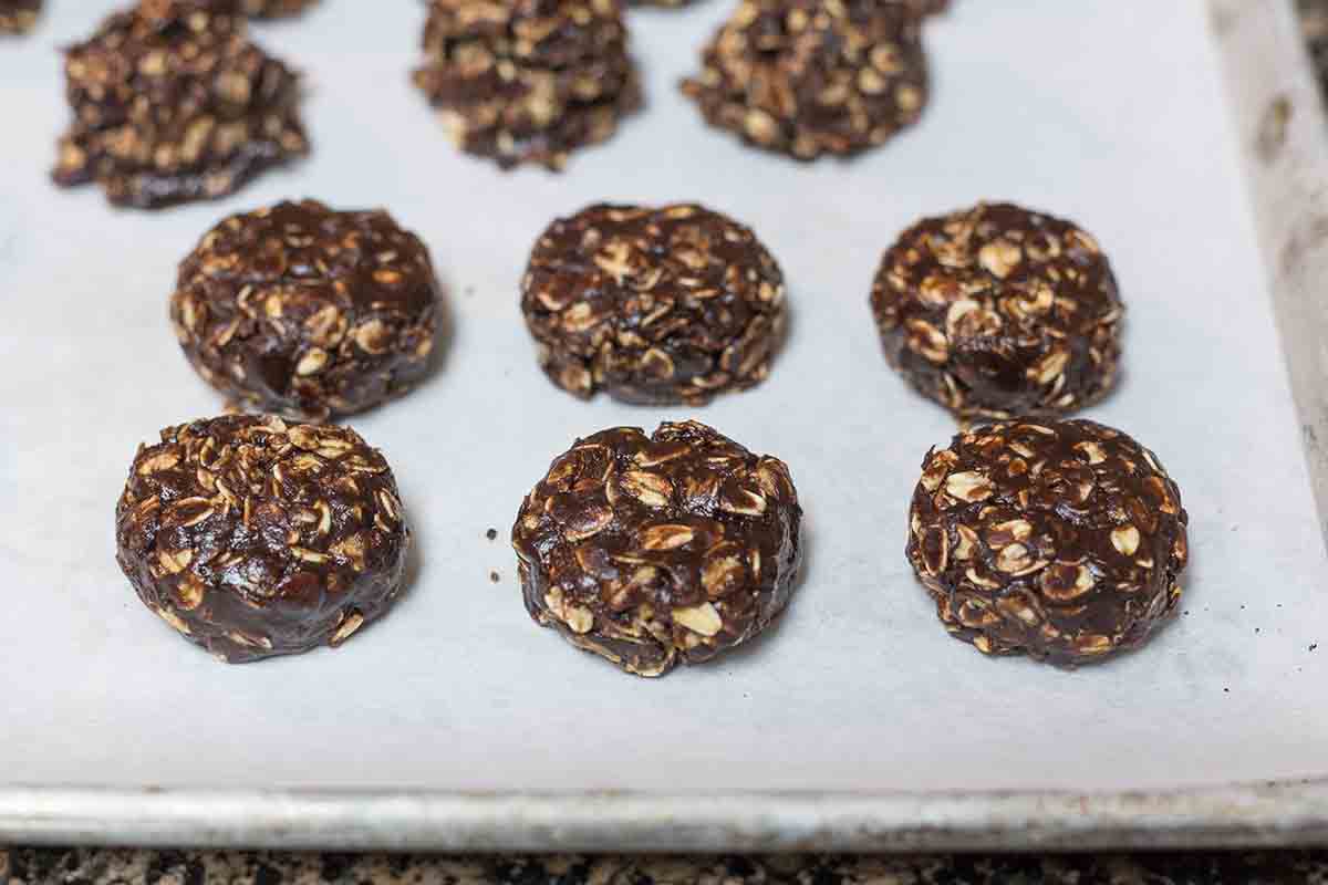 Chocolate no bake cookies cooling on a parchment lined baking sheet.