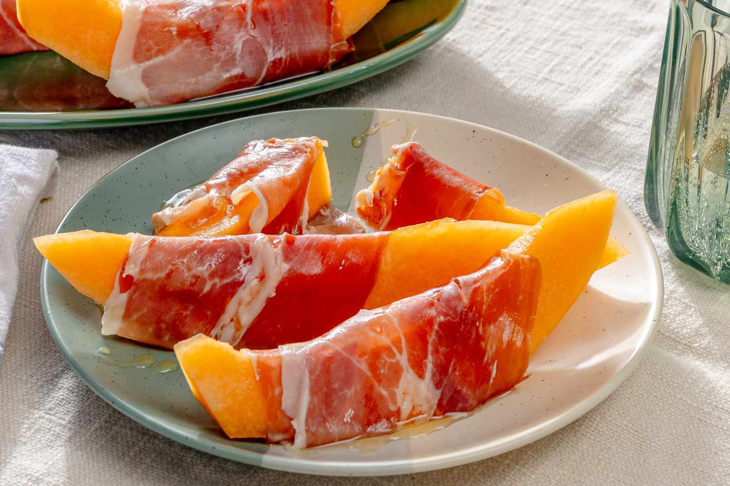 Slices of cantaloupe wrapped in prosciutto on a plate