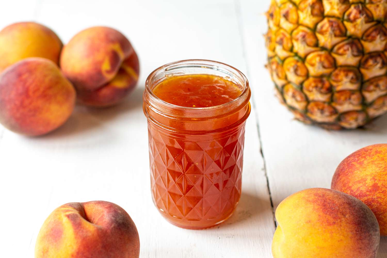 Peach and Pineapple Jam Surrounded by Peaches and a Pineapple