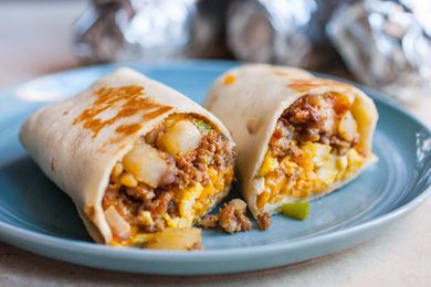 Potato, sausage, and egg burrito cut in half on a plate