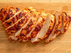 A juicy, spice-encrusted boneless skinless chicken breast sliced on a cutting board