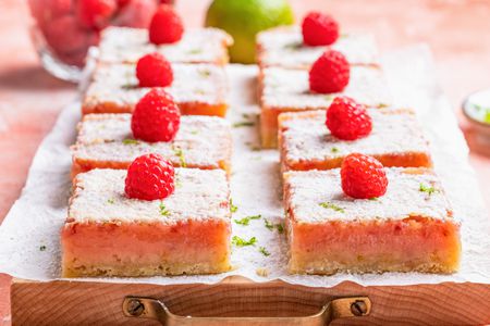 raspberry lime rickey bars on a parchment covered tray (close-up)