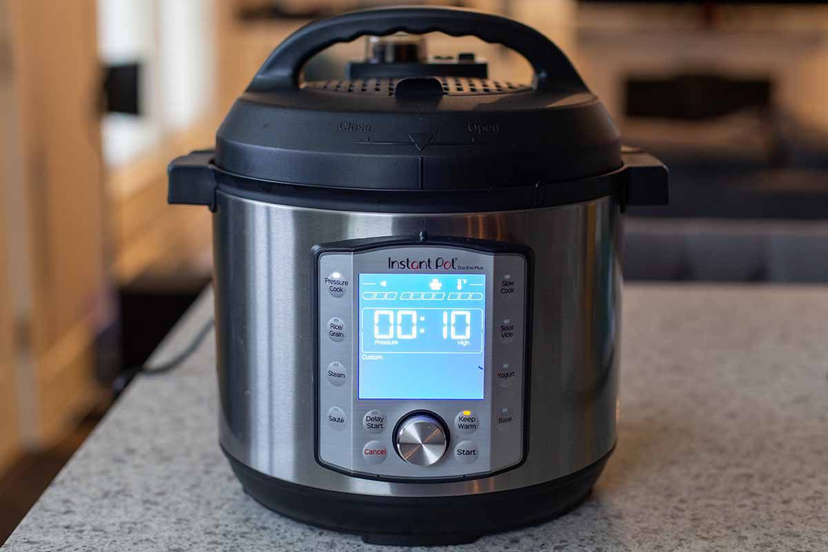 An instant sitting on a kitchen island. The pot is on and 10 minutes are displayed on the screen.