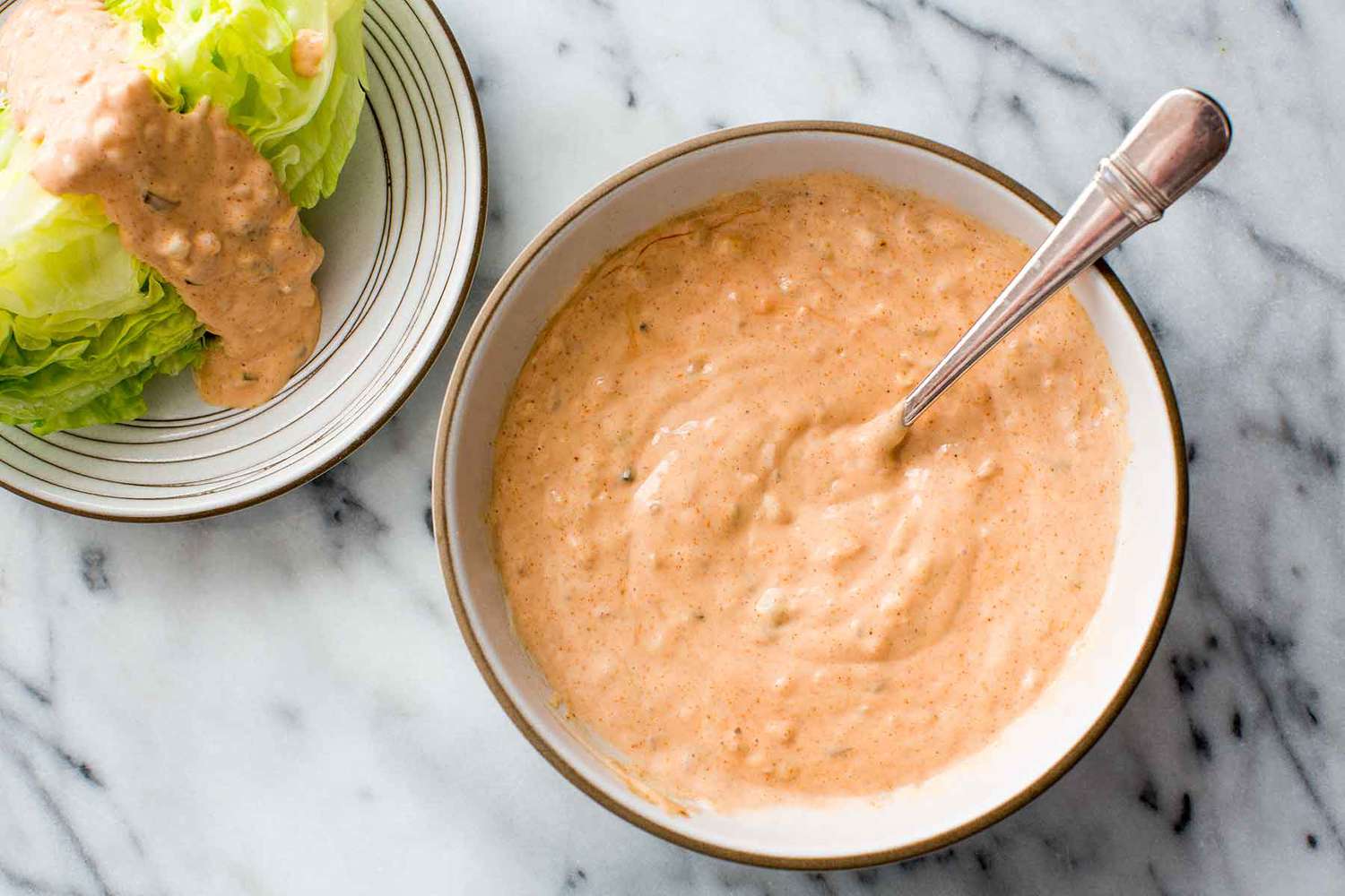 thousand island salad dressing in a bowl with a lettuce wedge on the side