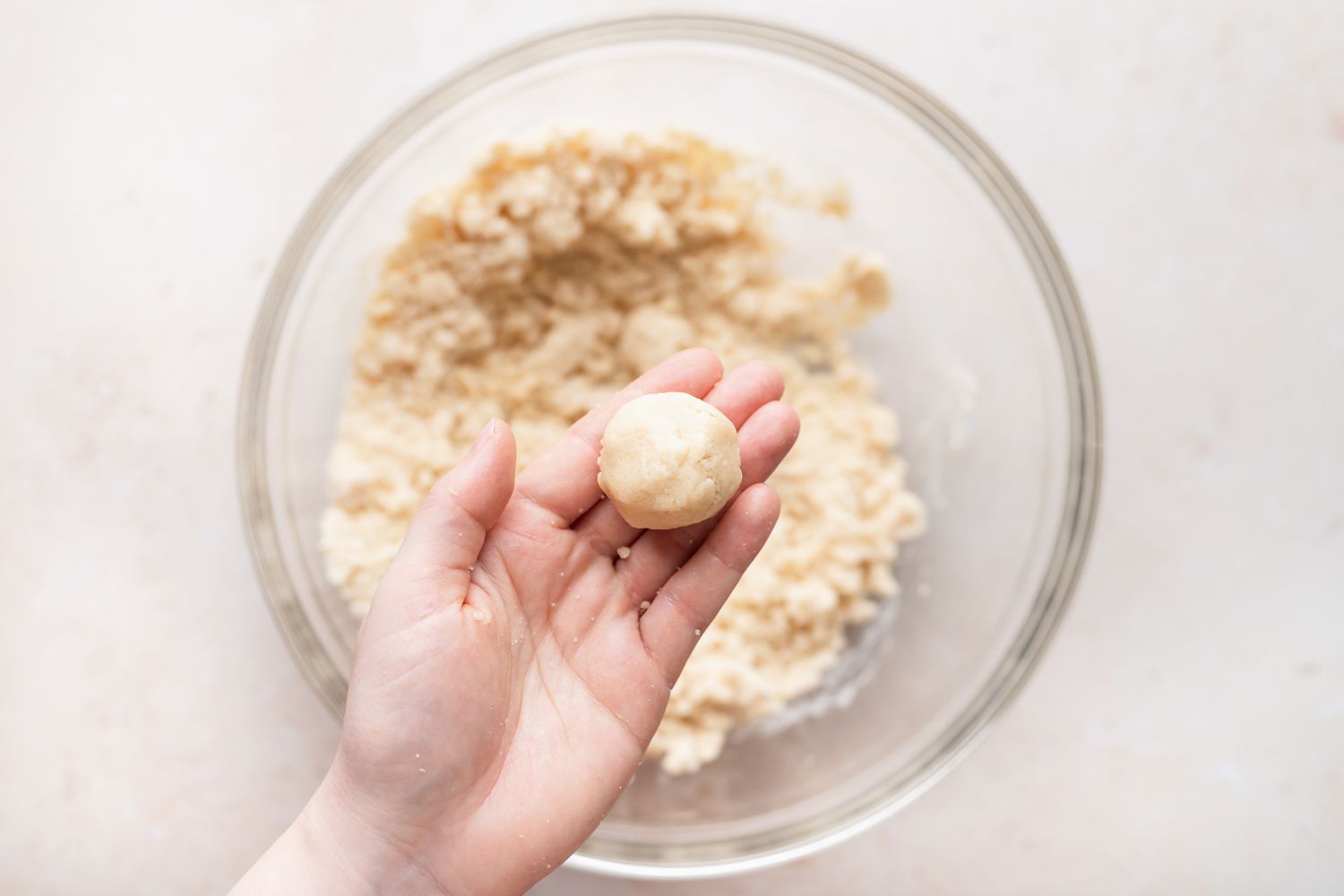 Rolling almond crescent cookies in a ball in a person's hand.