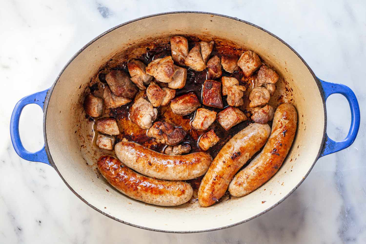 Sausages and pork cooking in Dutch oven.