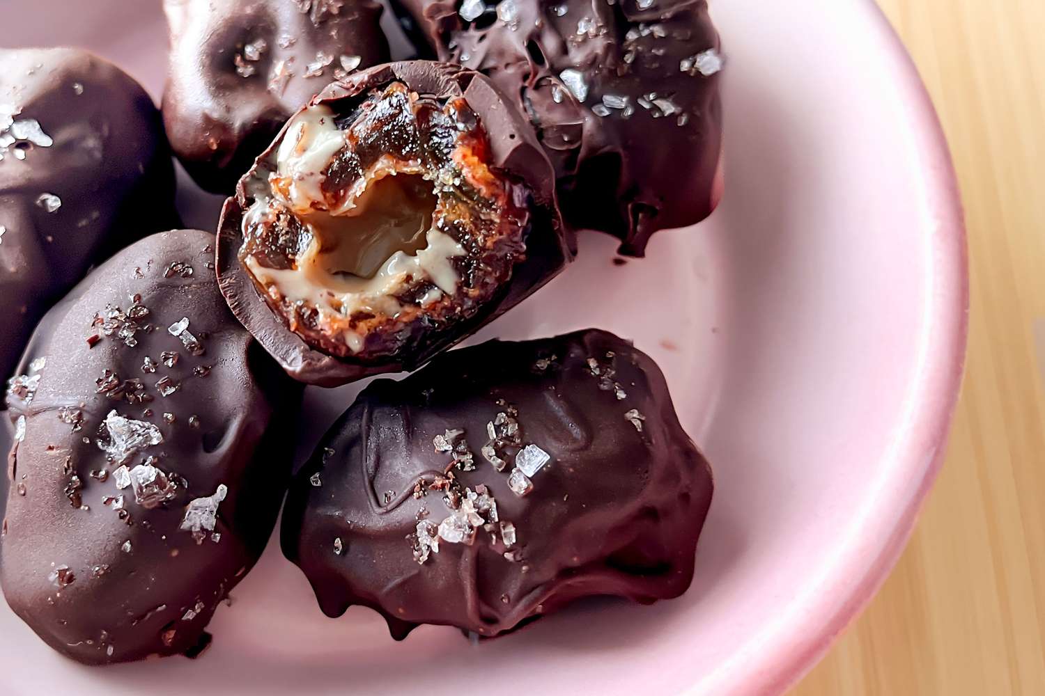 Tahini-Chocolate Dates, one cut open on top of several whole ones in a bowl