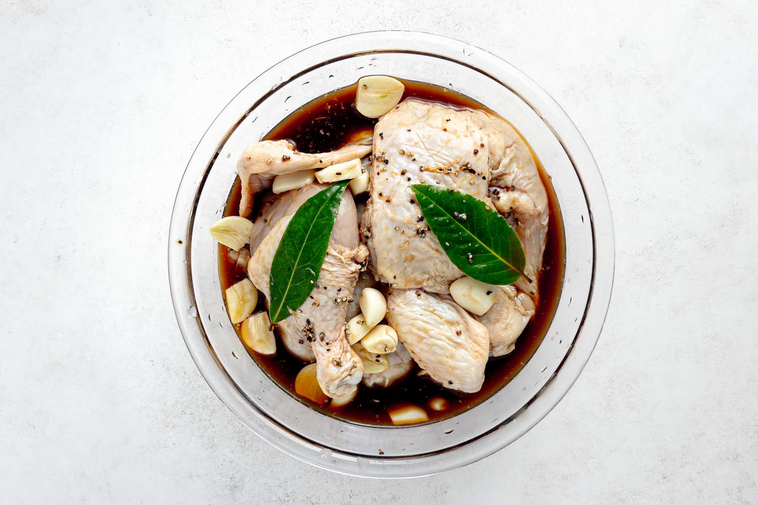 Bowl of Chicken Marinating in Soy Sauce, Vinegar, Black Pepper, and Bay Leaves for Adobo Recipe