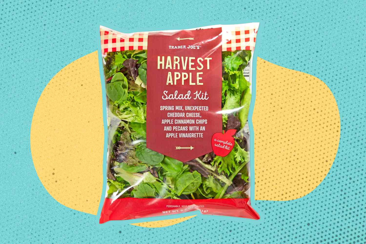 Front view of a package of Trader Joe's Harvest Apple Salad Kit on a blue and yellow speckled background