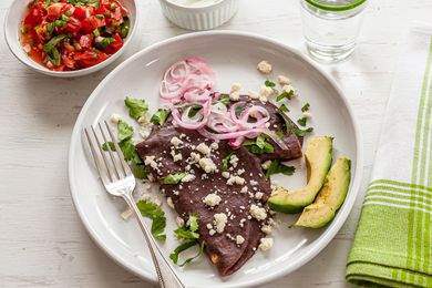 Mexican Enfrijoladas topped with avocado and cotija.