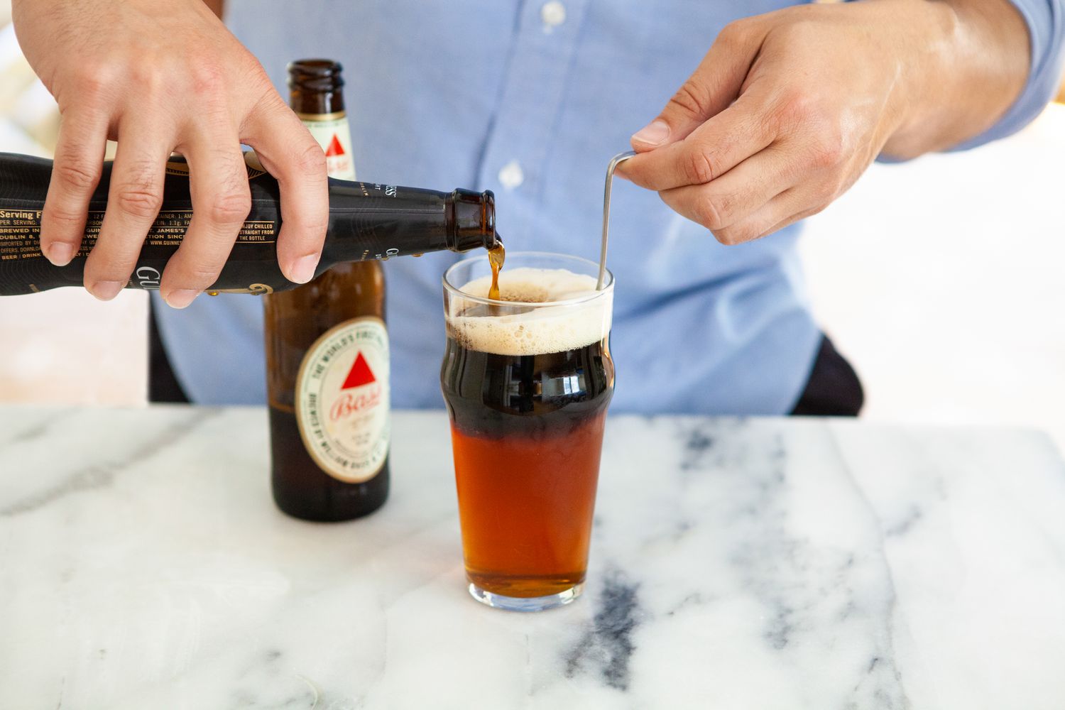 Bottle of Stout Carefully Poured into Glass of Black and Tan