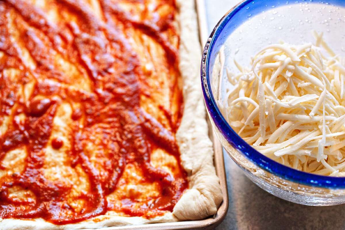 Sheet Pan Pizza with Mozzarella add the sauce and cheese